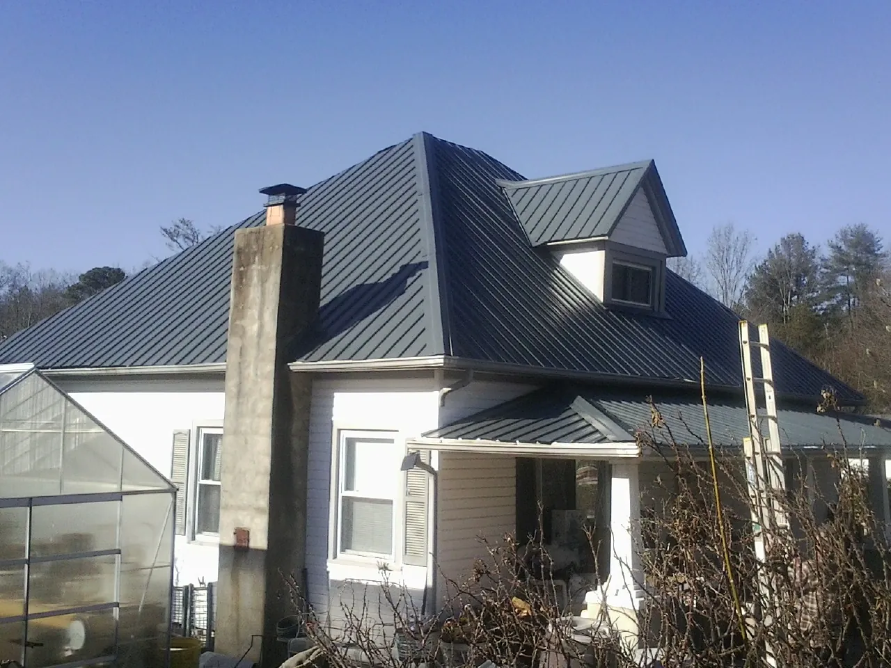 Dark blue standing seam metal roof on a white farmhouse with dormer — Slate & Tile Roof Repair by Roofing Brothers in Banner Elk