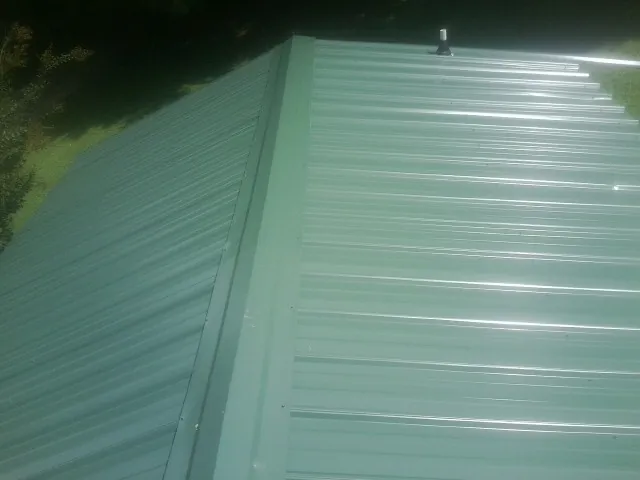 New green metal panels meeting at the ridge of a roof — Flat Roof Repair work by our crew in Banner Elk
