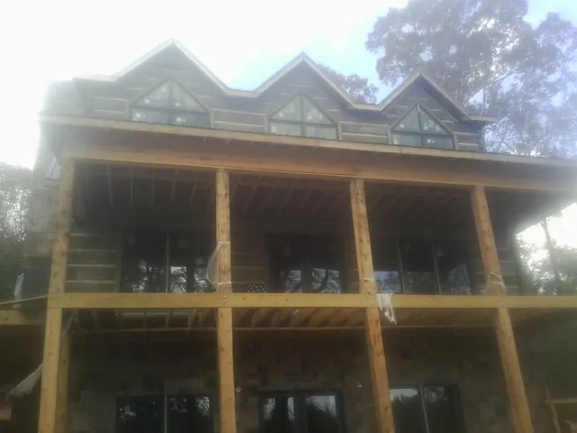 Dormers and porch framing on a large log home under construction — Roof Coating work by our crew in Banner Elk