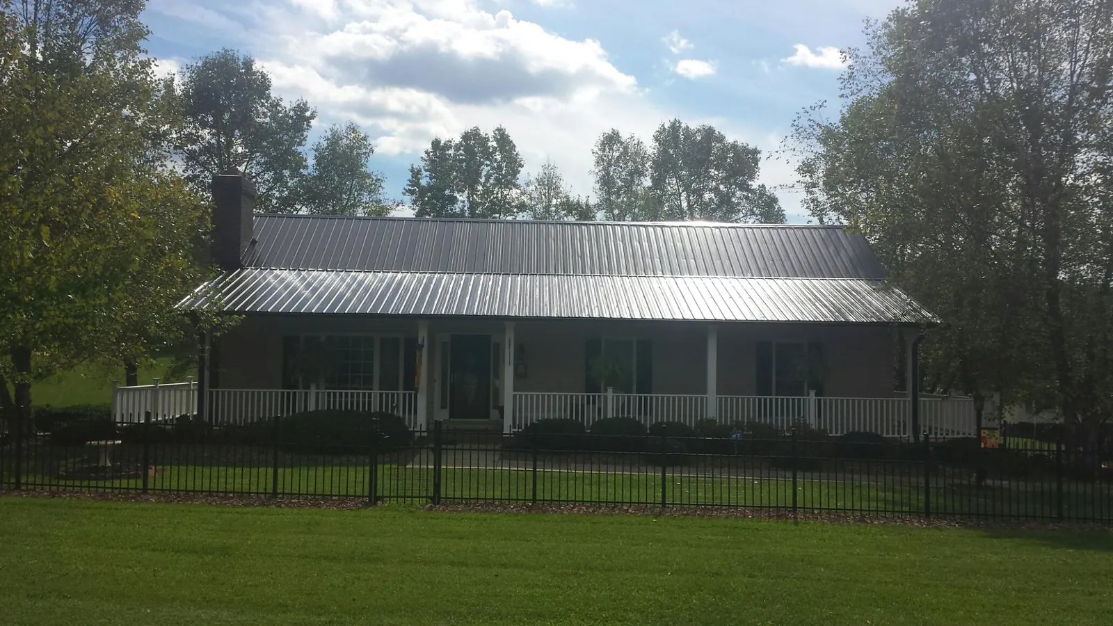 Gray metal roof on a brick ranch with a full width front porch in Banner Elk