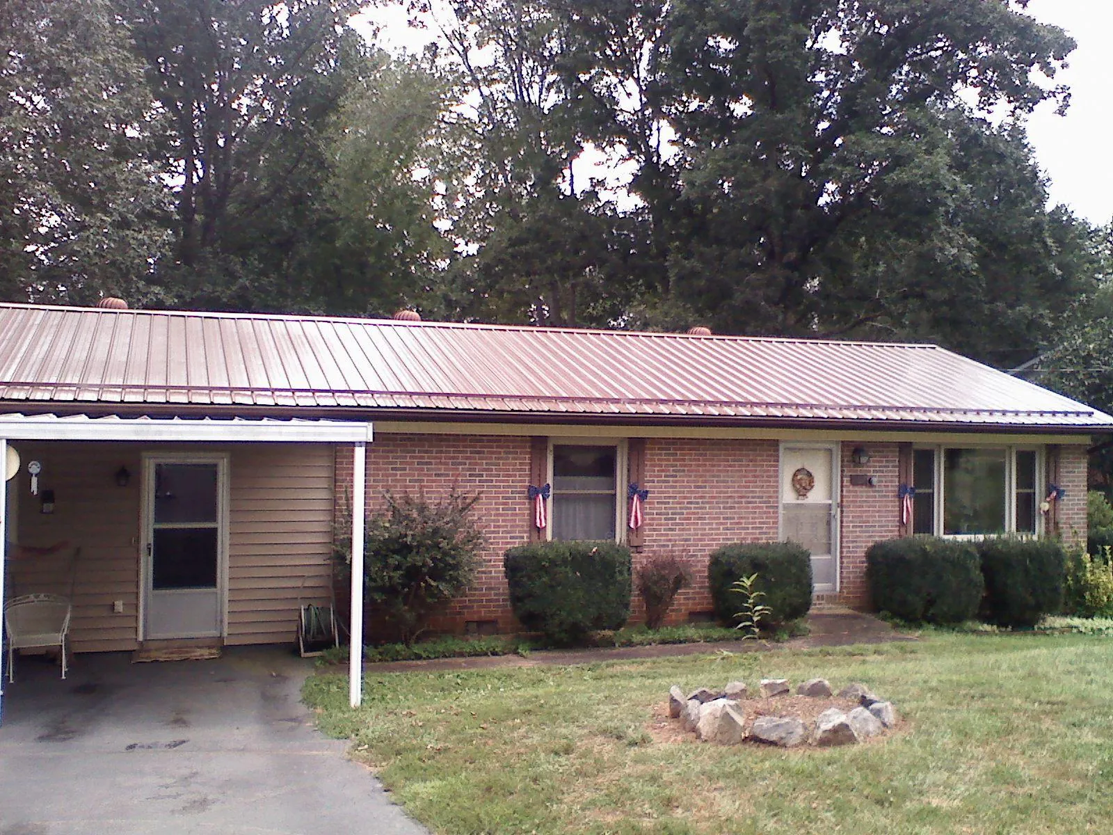 Bronze metal roof and carport on a brick ranch home — Roof Repair work by our crew in Banner Elk