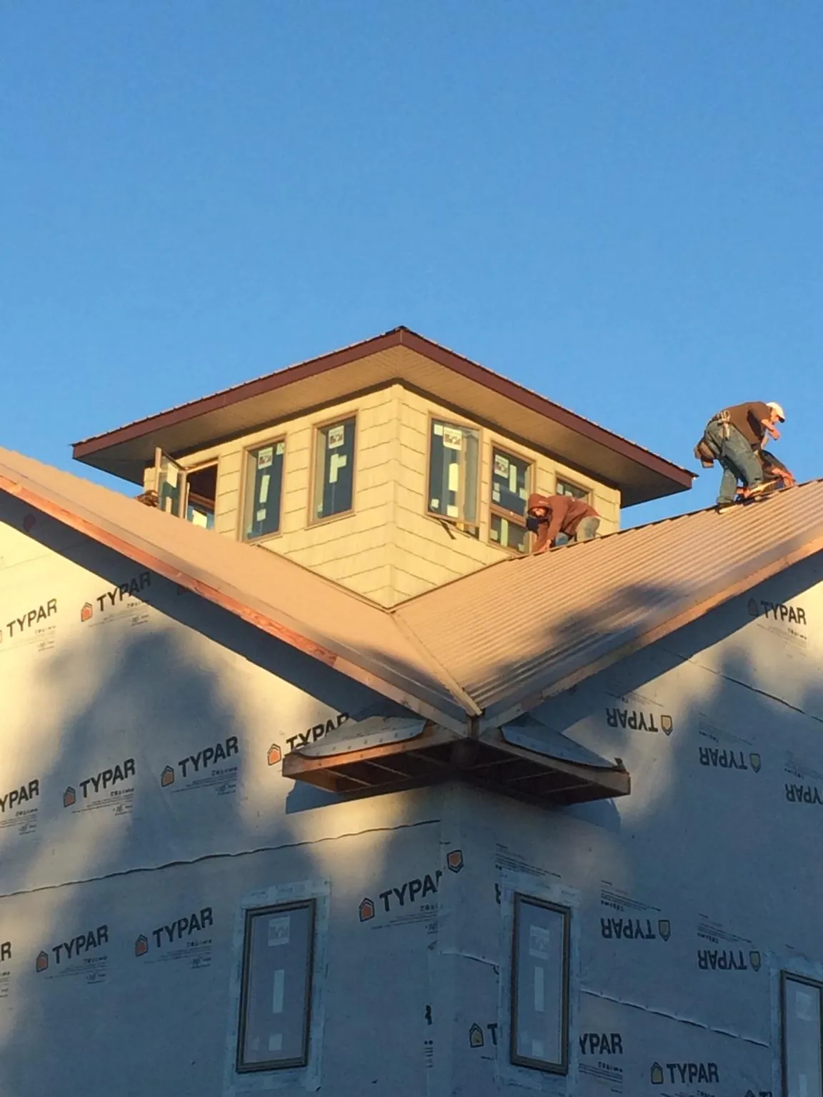 Roofers working around a rooftop cupola on a new metal roof at sunset — Roof Waterproofing in Banner Elk by Roofing Brothers